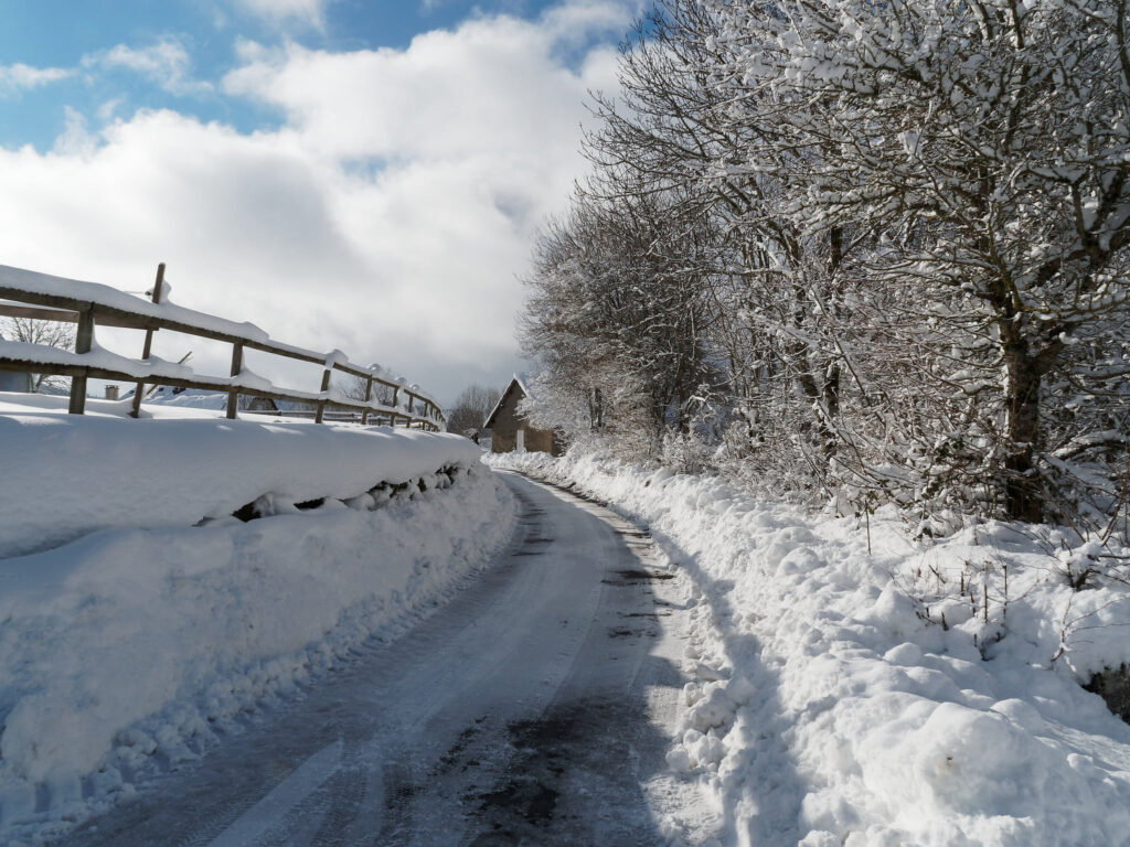 Route enneigée bordée d'arbres à Lagarde sur la commune de Lieutadès dans le Cantal
