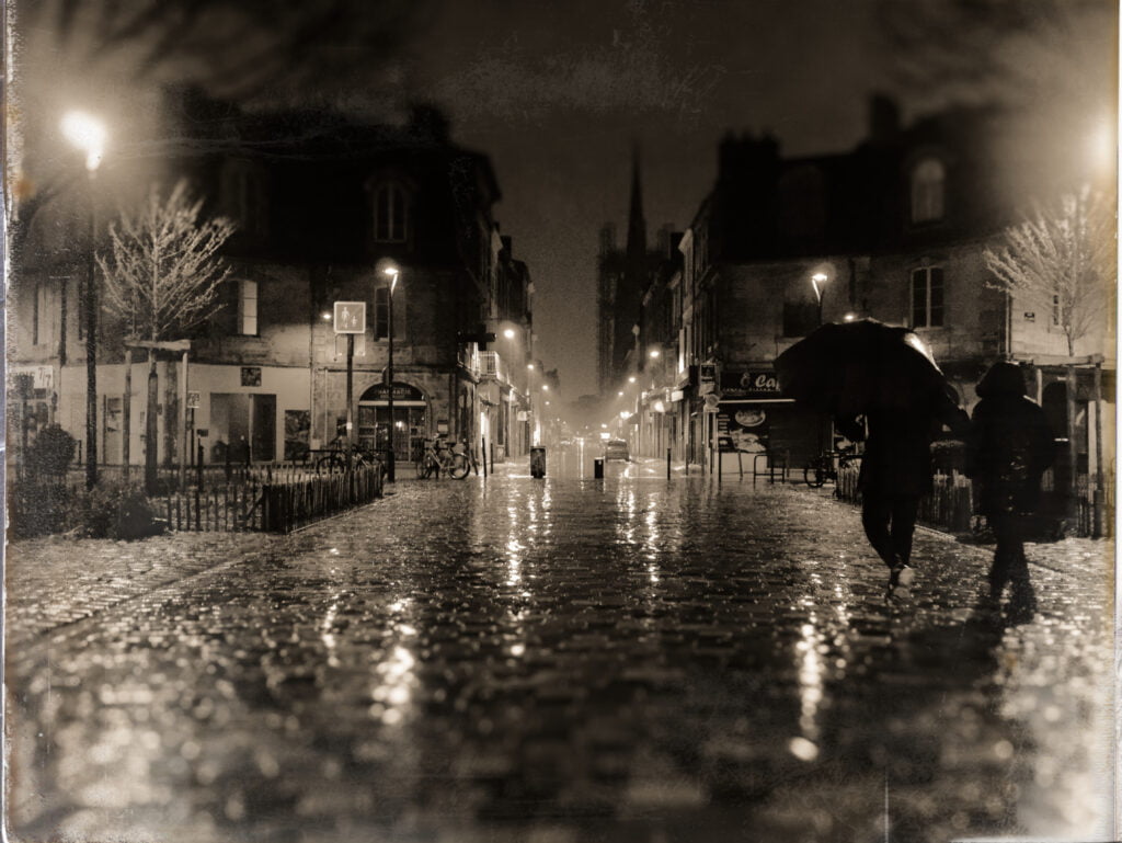 Silhouettes sous la pluie devant la flèche Saint-Michel à Bordeaux au petit matin